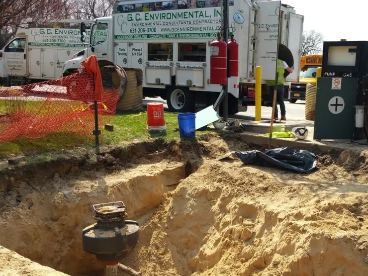 GCE service trucks beside an excavated pit exposing a tank sump and fuel dispenser