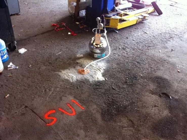 Sub-slab vapor sampling canister tubed to a bore hole marked SV1 on a garage floor