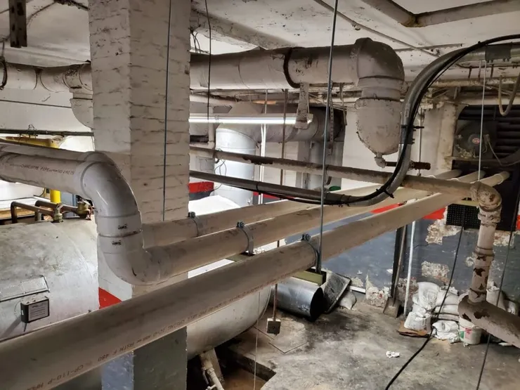 Insulated overhead piping running through a building basement mechanical space