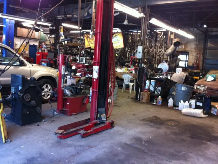 Interior of an auto repair garage with a red two-post lift and a vehicle