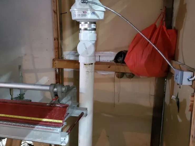 Sub-slab depressurization riser pipe with an inline mitigation fan on a framed wall