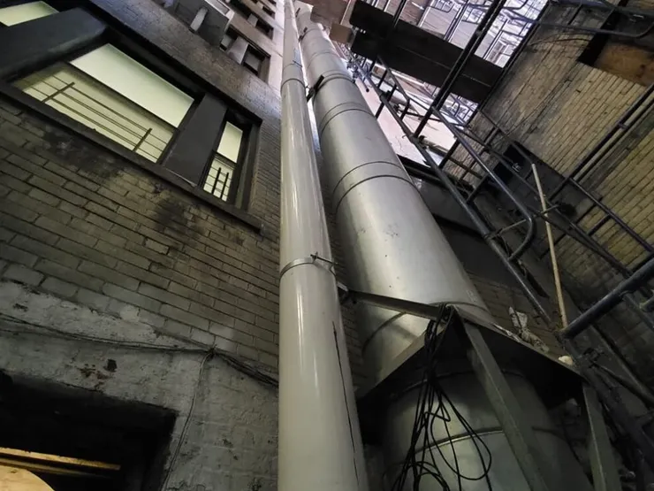Tall vent risers running up an interior airshaft of a brick apartment building